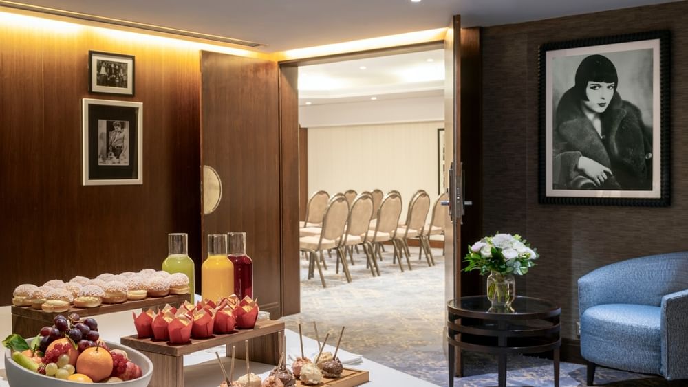 Juice carafes and pastries by a bowl of fruit under a portrait in Seminars & Banquets at Warwick Paris Champs Elysées