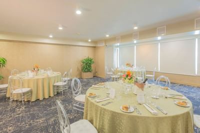 Banquet set-up with floral centerpieces and carpeted floors in Atlantis at Hotel Los Delfines & Casino