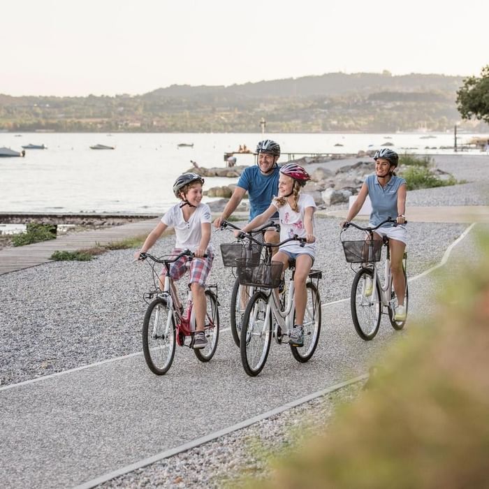 Family of four cycling by the lake at Falkensteiner Resort Lake Garda