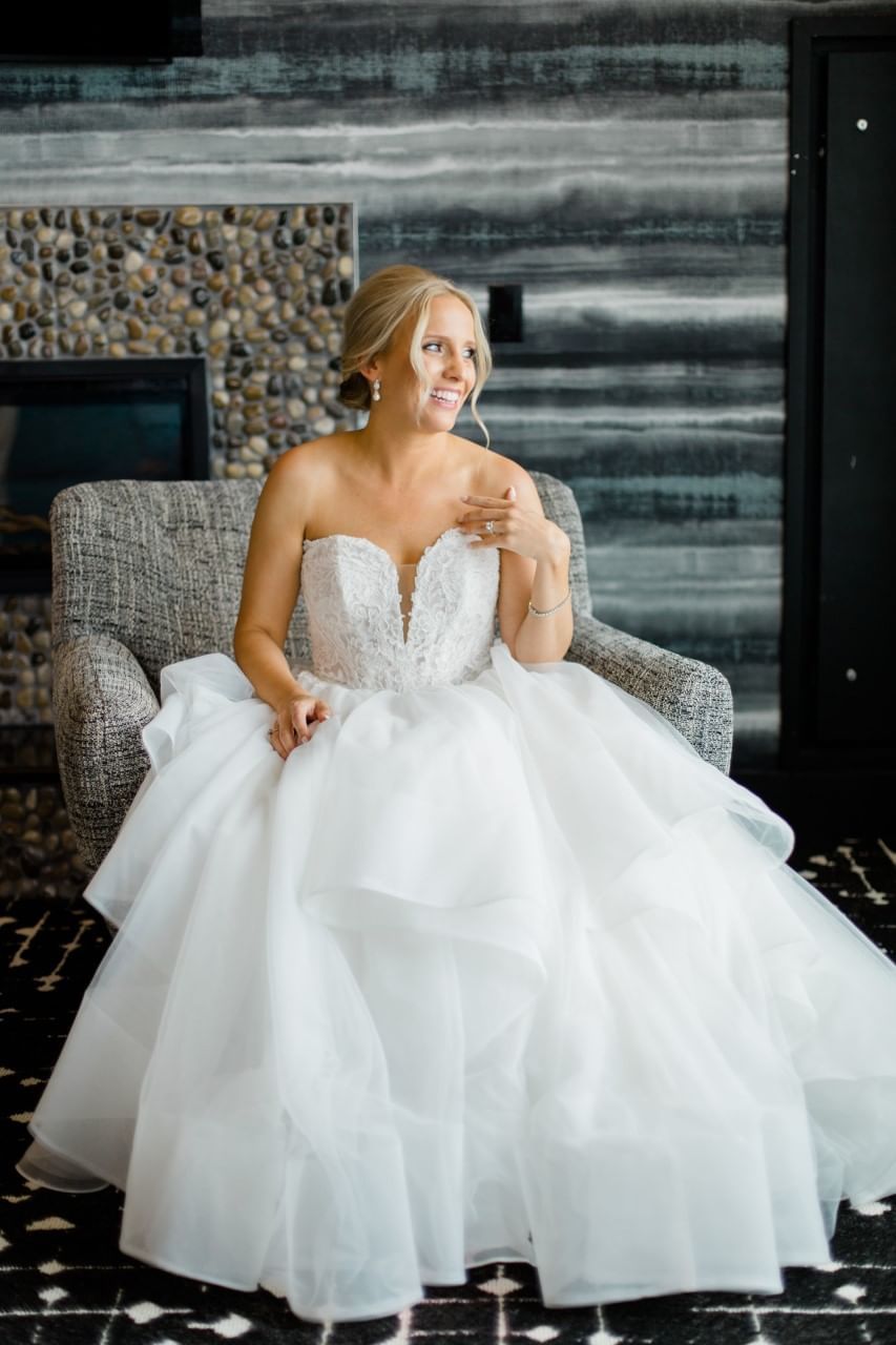 Bride sitting in a cozy lounger by a fireplace at The Earl