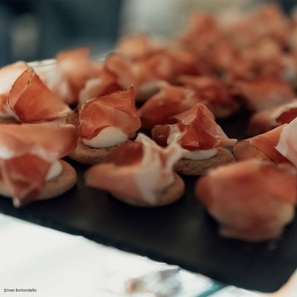Close-up of appetizers with prosciutto and cream on a platter.