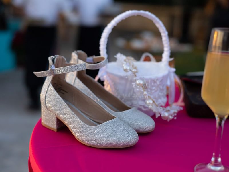 Pair of silver heels, a basket, and a wine glass on a pink table at Riviera Nayarit Resort & Spa.