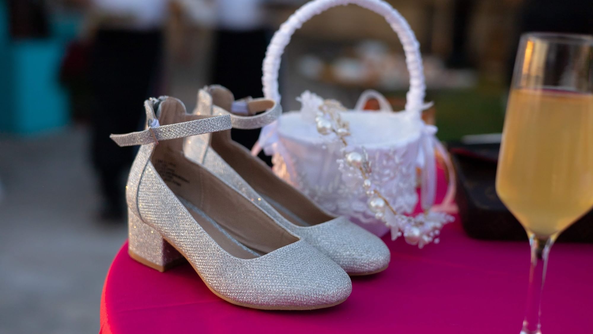 Pair of silver heels, a basket, and a wine glass on a pink table at Riviera Nayarit Resort & Spa.