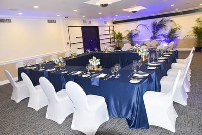 A banquet room with elegant blue and white tablecloths in Somerset Suite at Courtleigh Hotel & Suites
