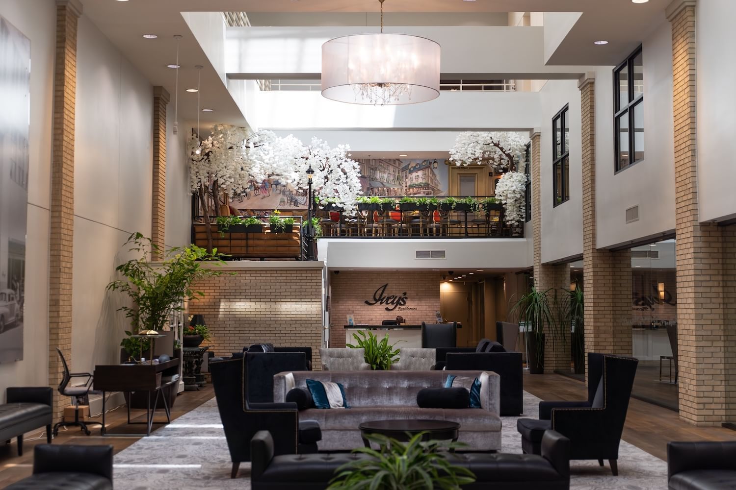 A spacious hotel lobby with a high ceiling, modern furniture, and a balcony with plants.