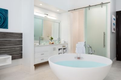 Freestanding tub beside marble double vanity with glass vessel sinks in King Superior Ground Floor at Zenza Hotel