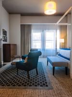 Teal armchairs by a marble fireplace under a wall-mounted TV in Loft Fireplace Suite at Warwick San Francisco