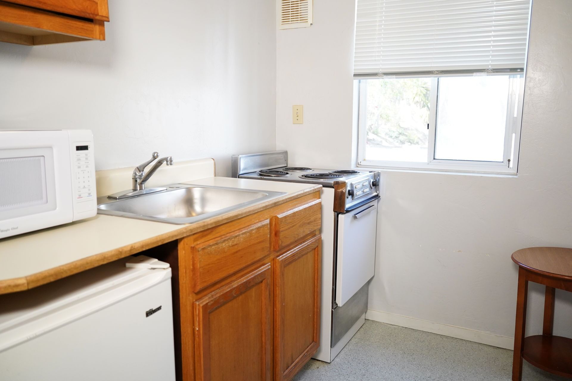 A small kitchenette with a microwave, sink, stove, and refrigerator.