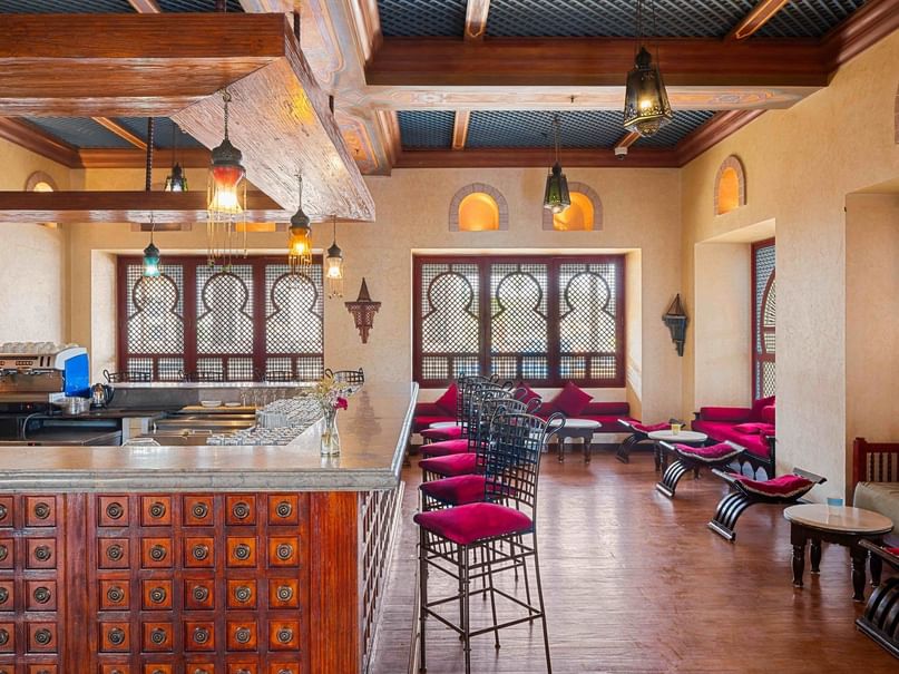 بار اللوبي مع كراسي حمراء وطاولة بار خشبية معقدة في فندق بيكالباتروس ساندز بورت غالب.