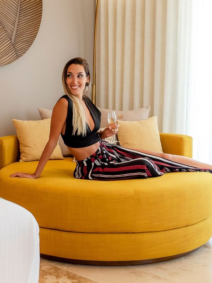 A woman on a yellow sofa holding a wine glass at The Reef 28