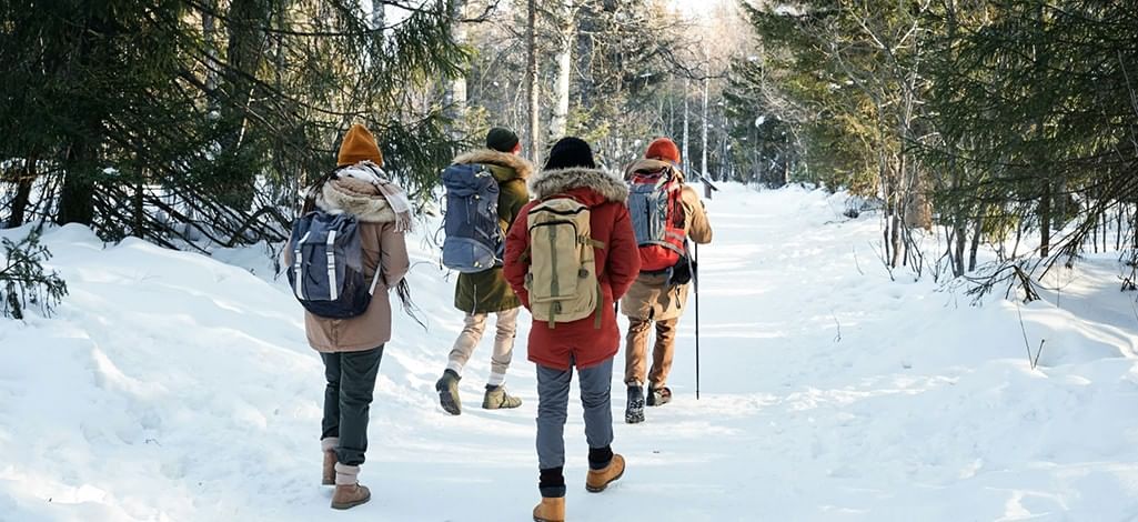 A group dresses for winter in Canmore, setting out along a snowy trail.
