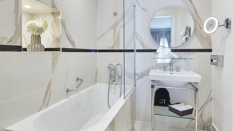 Interior of Prestige Suite bathroom with a bathtub, mirrored sink and marble surface at Hôtel Westminster - Paris