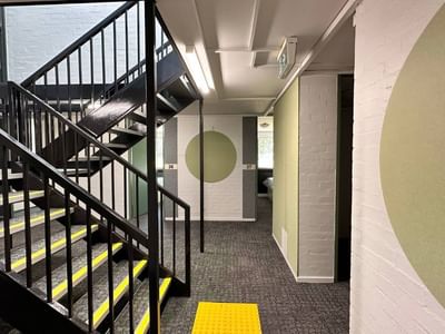 Modern staircase with yellow tactile strips and green walls at La Trobe University – Menzies College.