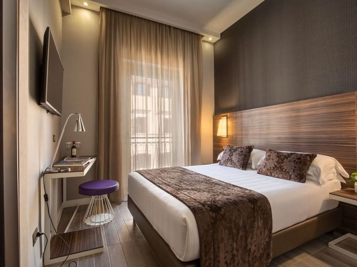 Classic Room featuring a queen bed with pillows, a sleek desk with a purple stool, and curtains at The Republic Hotel