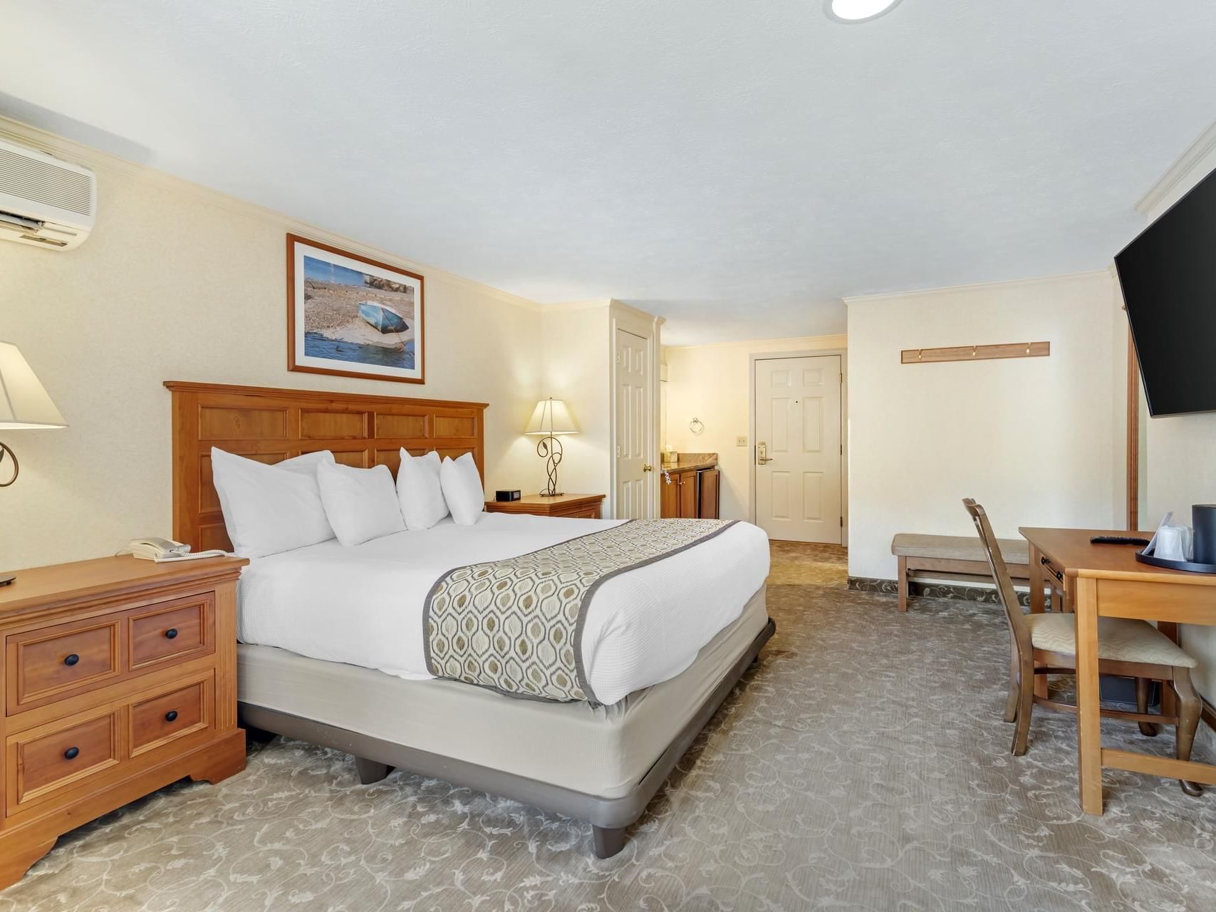 King bed with comfy pillows, work desk & TV in a Main Resort Room King at Meadowmere Resort