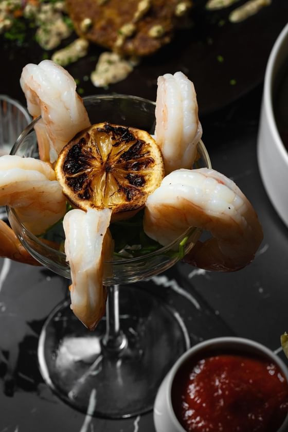 Glass filled with shrimp arranged in a circular pattern, topped with a grilled lemon slice at Cypress and Oak, Frankfort, KY