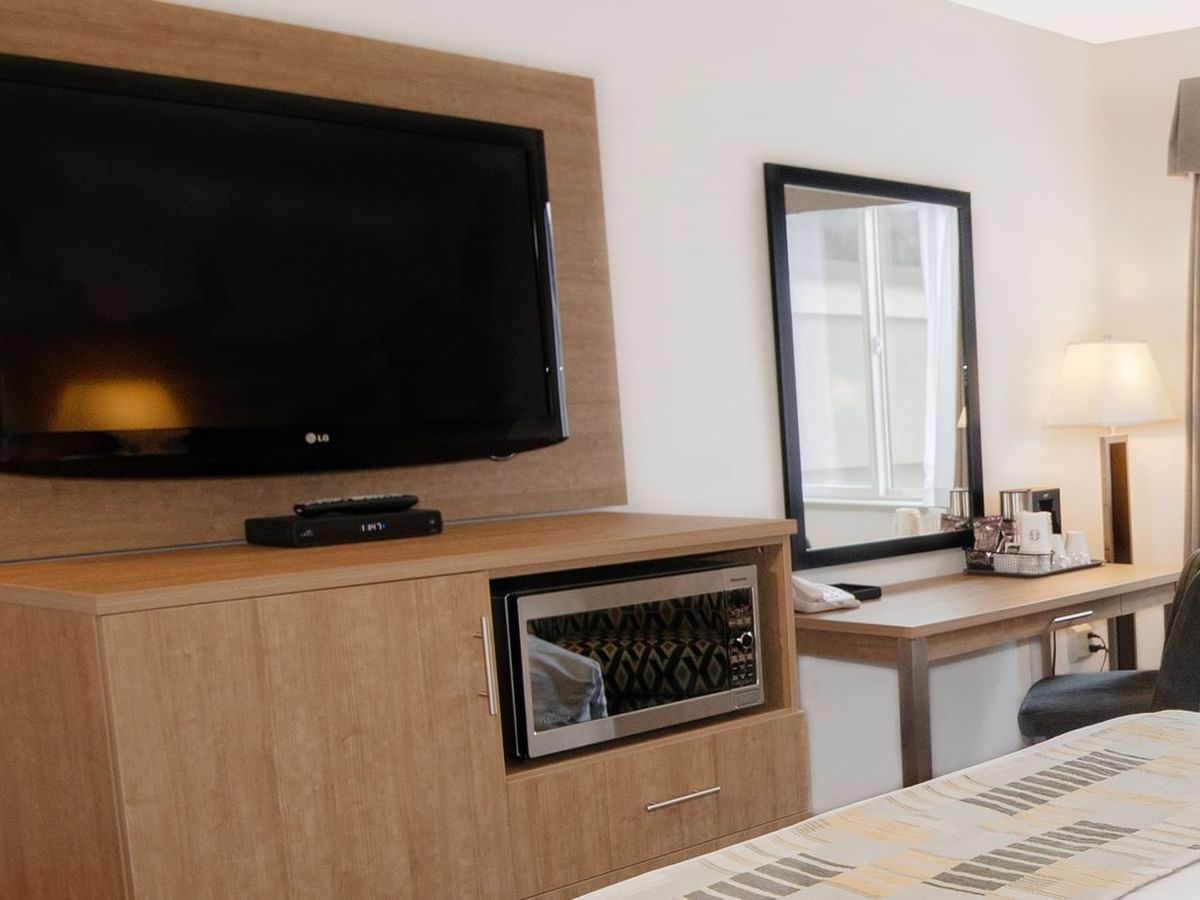 Hotel room with mirror, chair, table, microwave, and TV