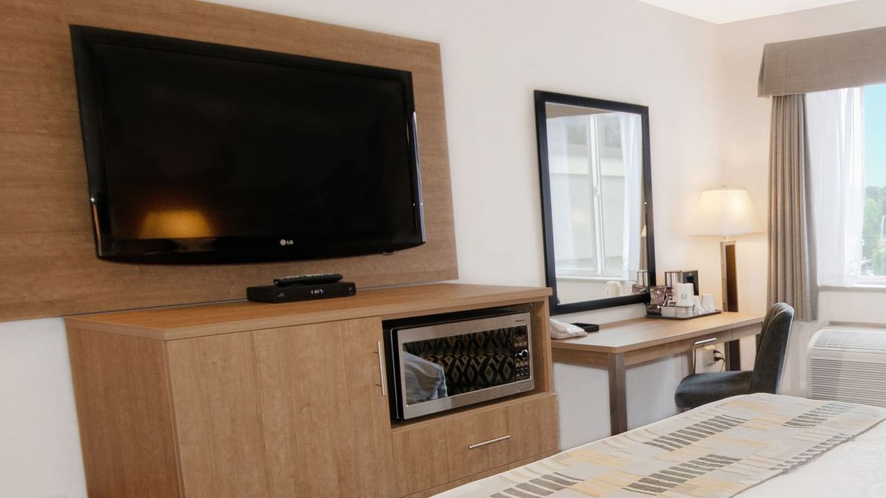 Hotel room with mirror, chair, table, microwave, and TV