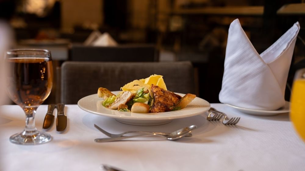 Fresh Caesar salad with grilled chicken served on a white dinner plate in Al Firdous Restaurant at Saja Warwick Madinah 