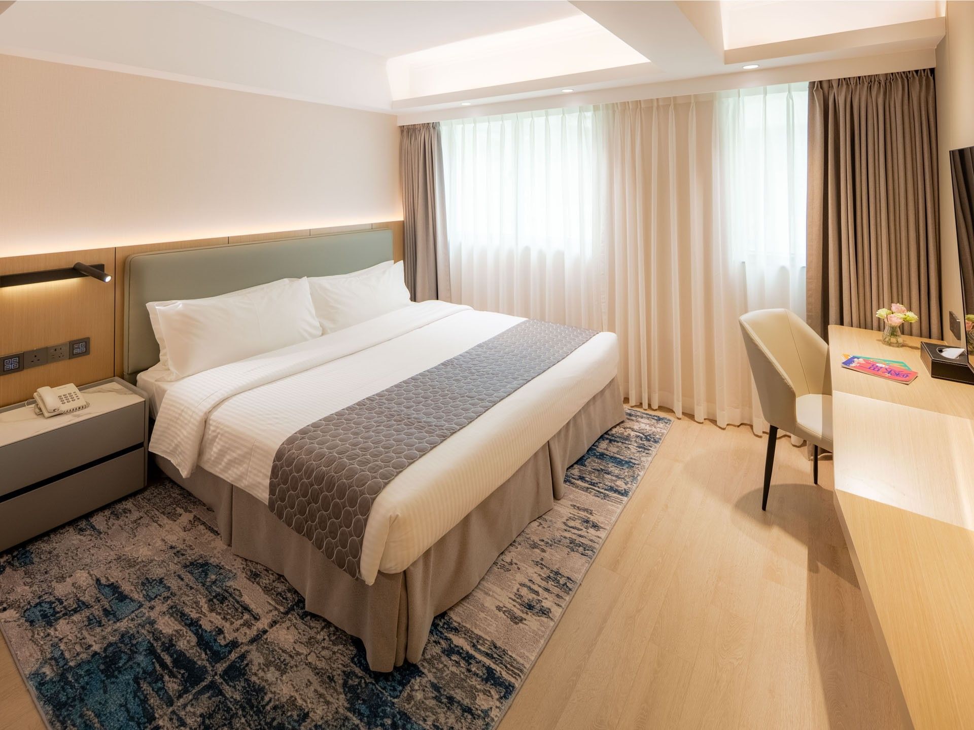 TV and workspace facing the bed in Deluxe Room with wooden floors at Inn Hotel Macau, offering stylish hotel rooms in Macau