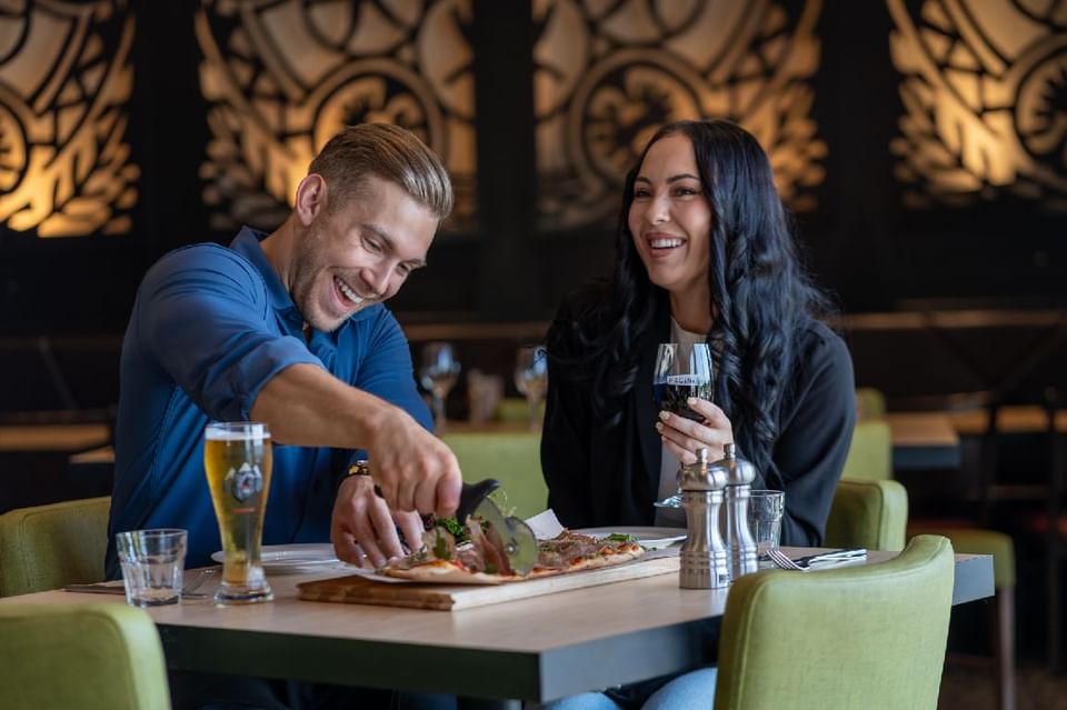 A couple enjoying pizza in Pacini Restaurant near Acclaim Hotel Calgary