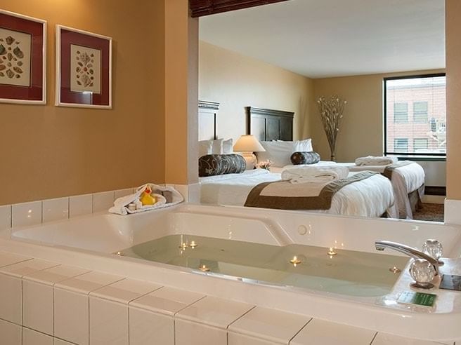 Bathtub filled with water by the comfy beds in Family Mineral Spa Suite at Temple Gardens Hotel & Spa