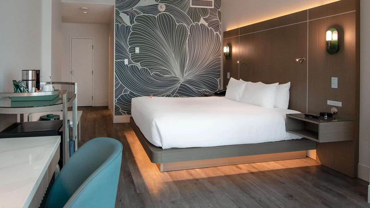 Hotel bedroom with large bed, wooden floors, and floral wall design.