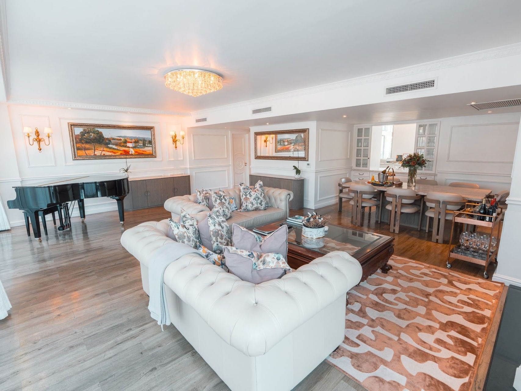 Luxury Presidential Suite living room featuring white tufted sofas, a grand piano, and a dining area at Pepperclub Hotel