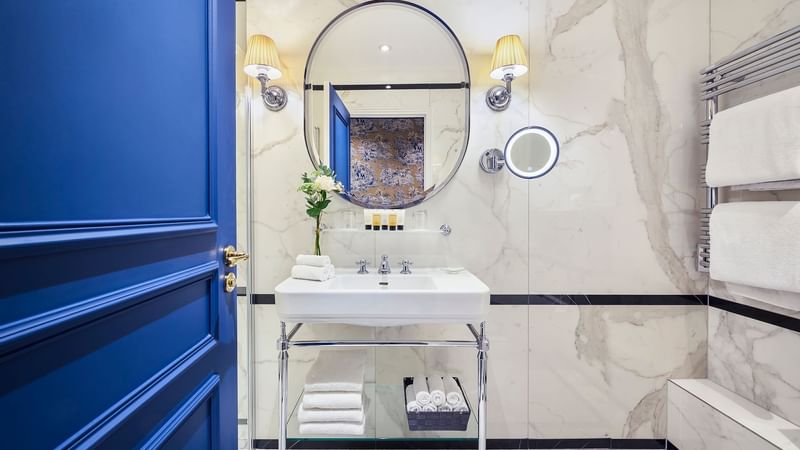 Deluxe Room bathroom featuring a round mirror, modern sink, and marble walls at Hôtel Westminster - Paris