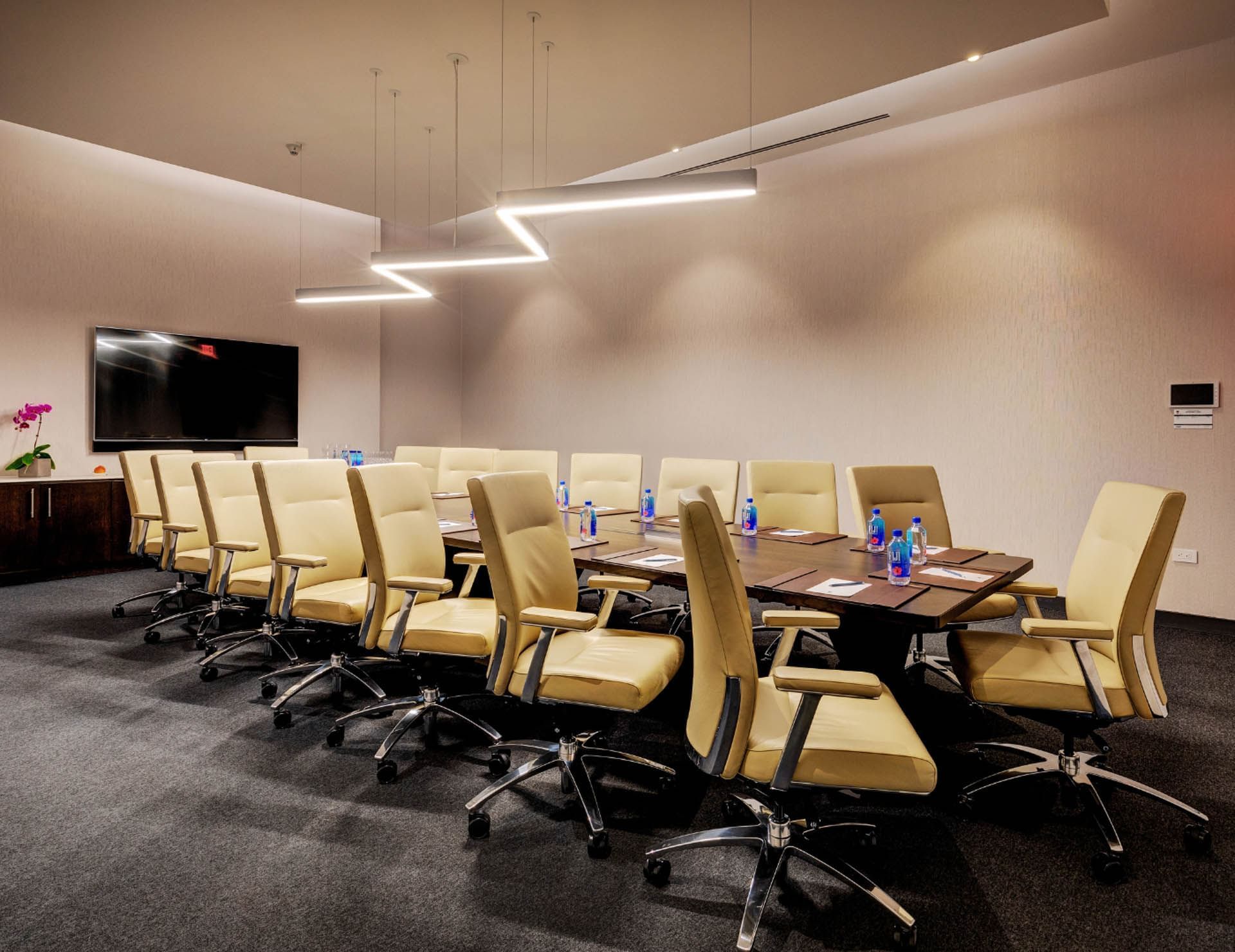 Champion's Boardroom with with leather swivel chairs around a long wooden table facing the TV screen at Hotel X Toronto