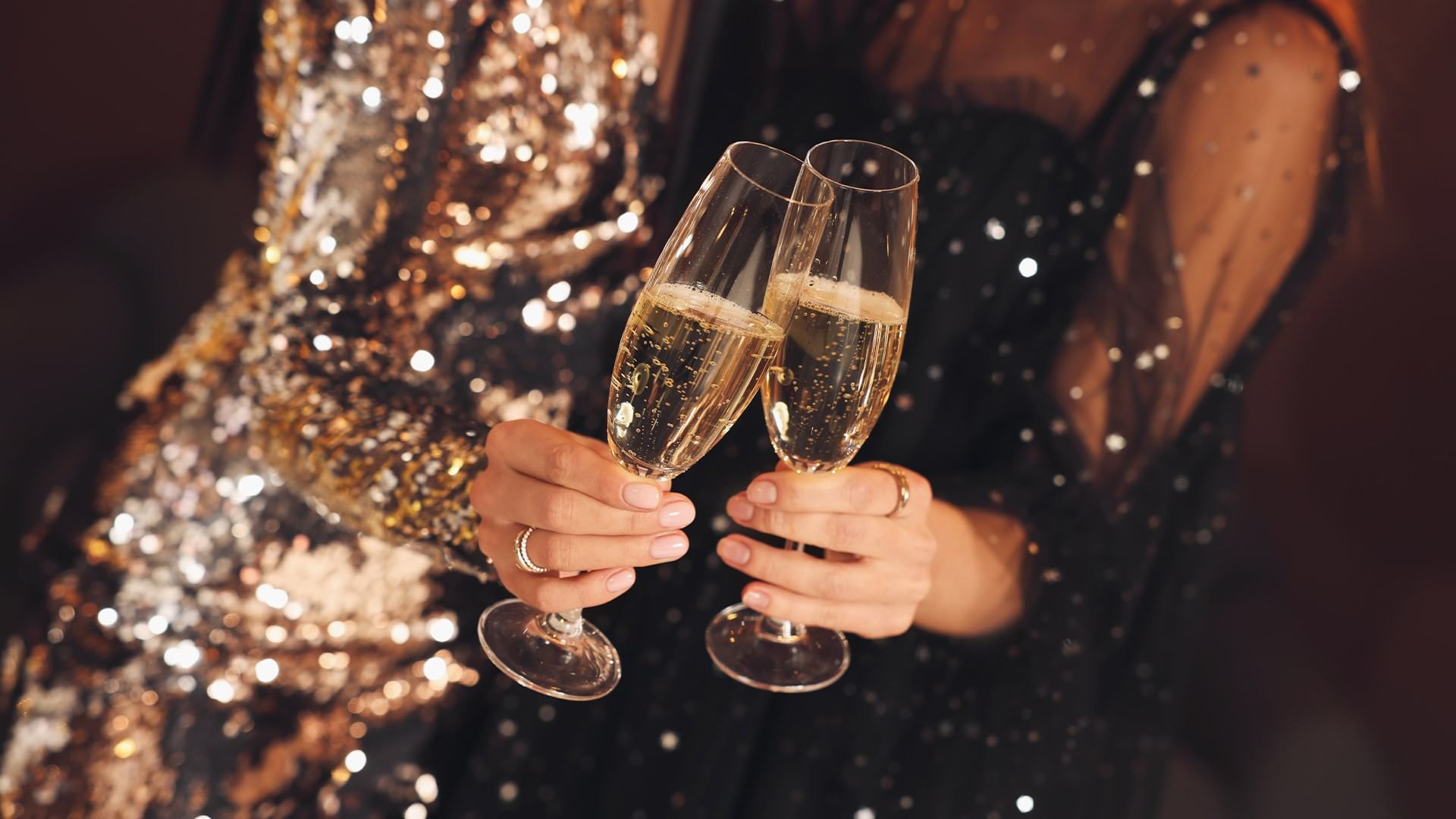 Two women in elegant attire toasting with champagne flutes at Falkensteiner Schlosshotel Velden