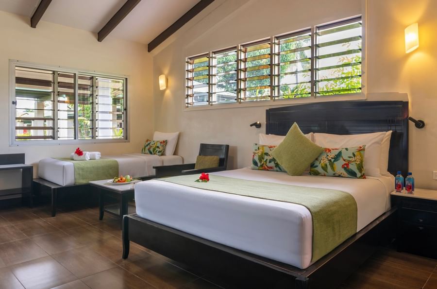 Two comfortable beds with tropical decor and shutters at Tokatoka Resort Fiji International Airport.