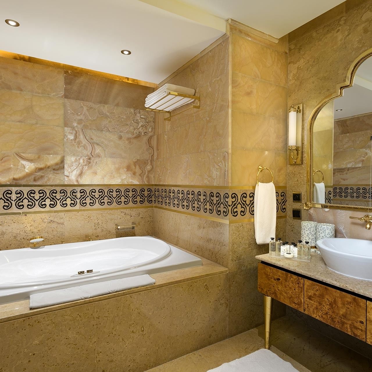 Ванная комната королевского двухуровневого люкса с большой ванной, раковиной, зеркалом и декоративной плиткой на стенах