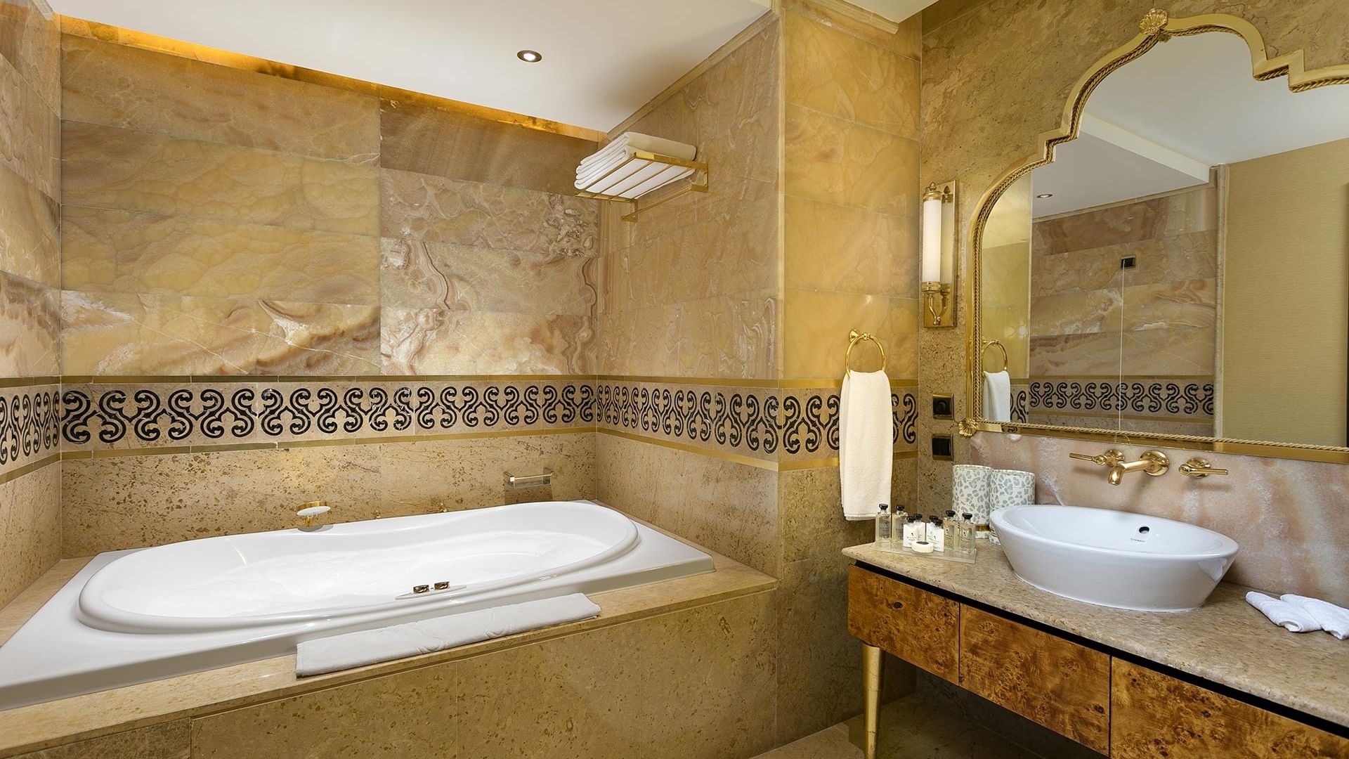Ванная комната королевского двухуровневого люкса с большой ванной, раковиной, зеркалом и декоративной плиткой на стенах