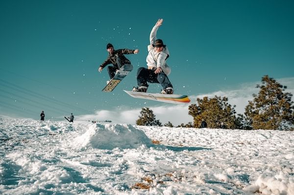 Men snowboarding down a snowy hill near Blackcomb Springs Suites