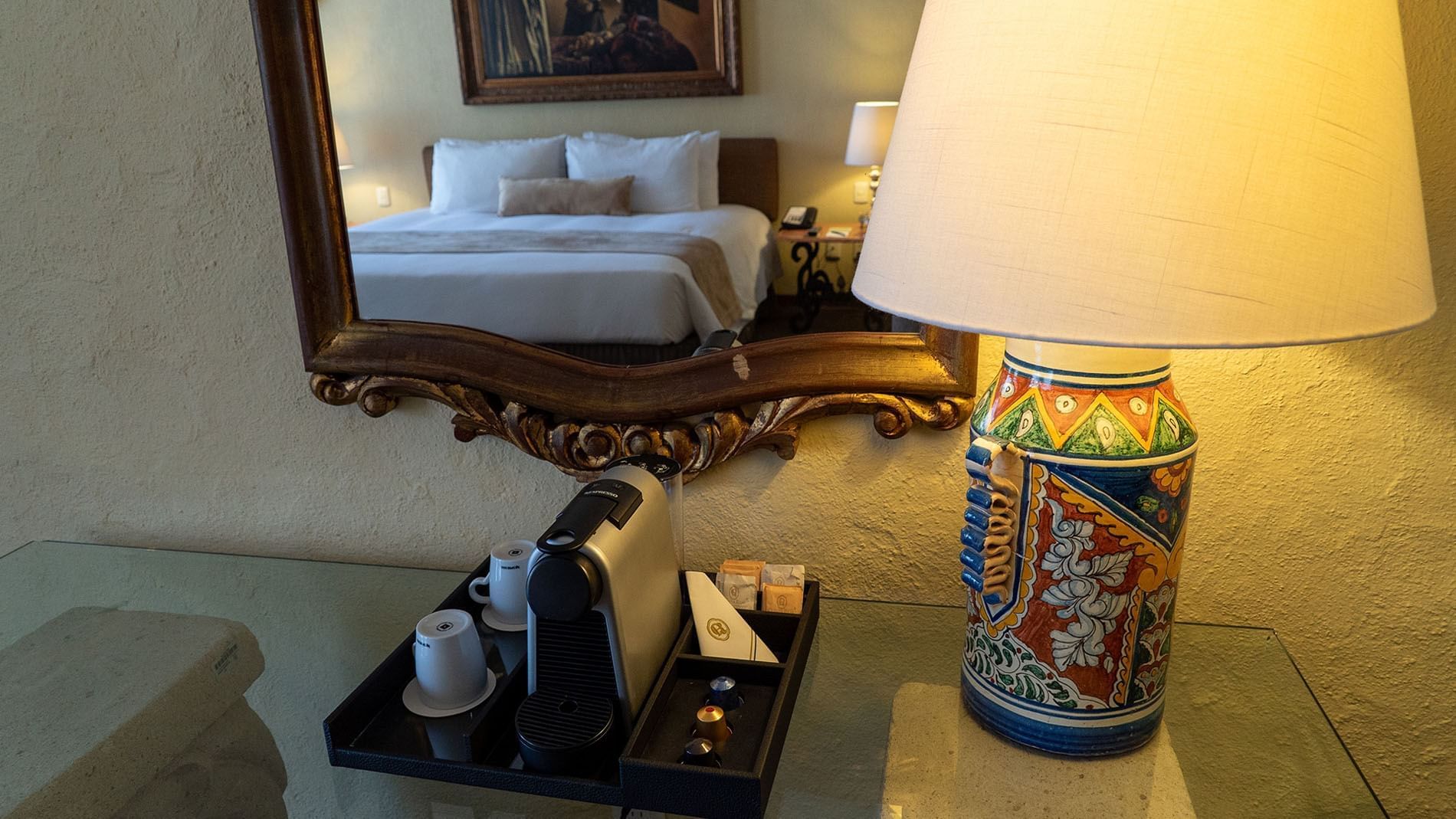 King Master Suite Nespresso machine and colorful talavera lamp reflected in a gold mirror at Quinta Real Aguascalientes