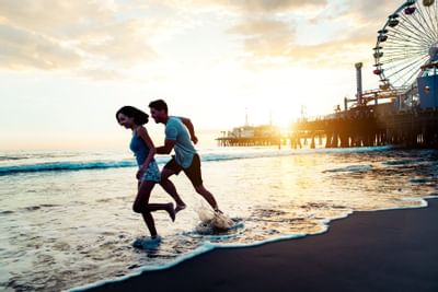 Friends playing in the surf with Santa Monica Pier behind them