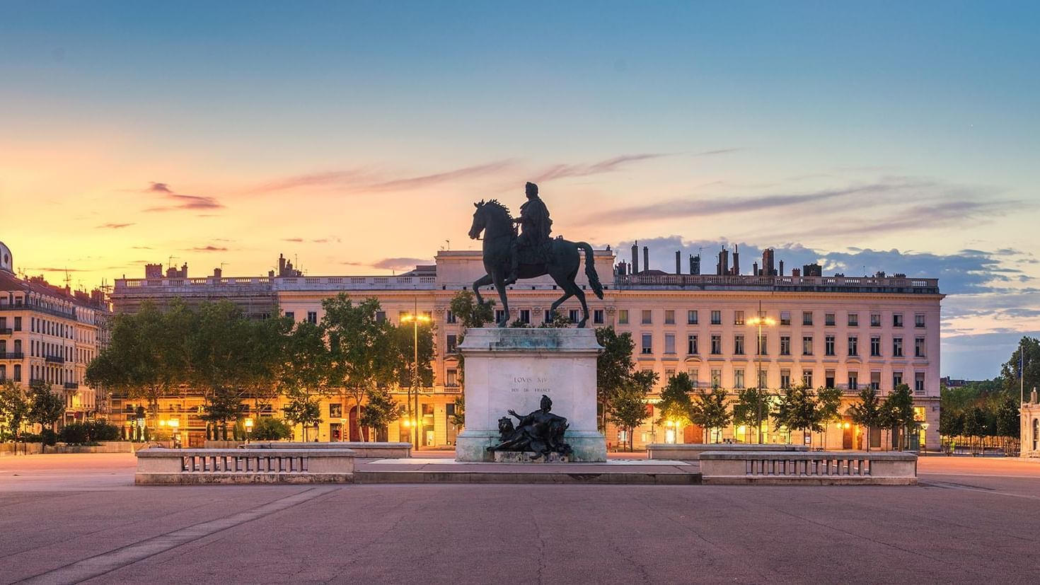 Statue of Louis XIV on horseback at sunset, surrounded by trees and historic buildings near Warwick Hotels and Resorts