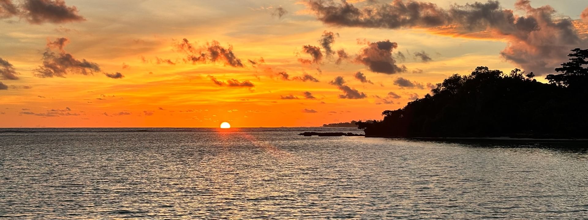 Sunset over ocean with lush coastline at Warwick Le Lagon - Vanuatu, Efate
