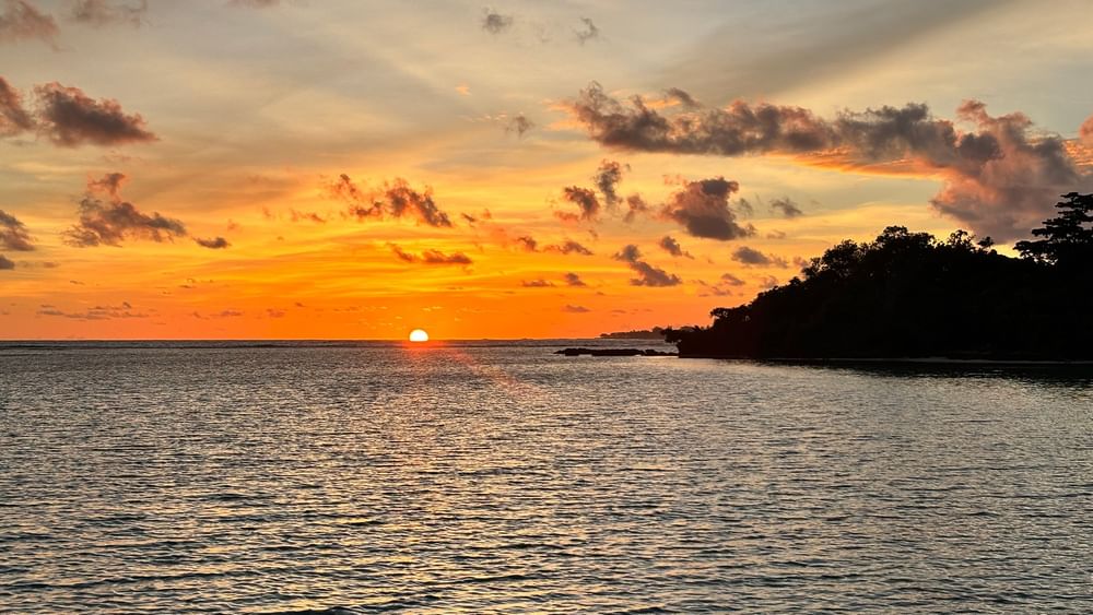 Sunset over ocean with lush coastline at Warwick Le Lagon - Vanuatu, Efate.