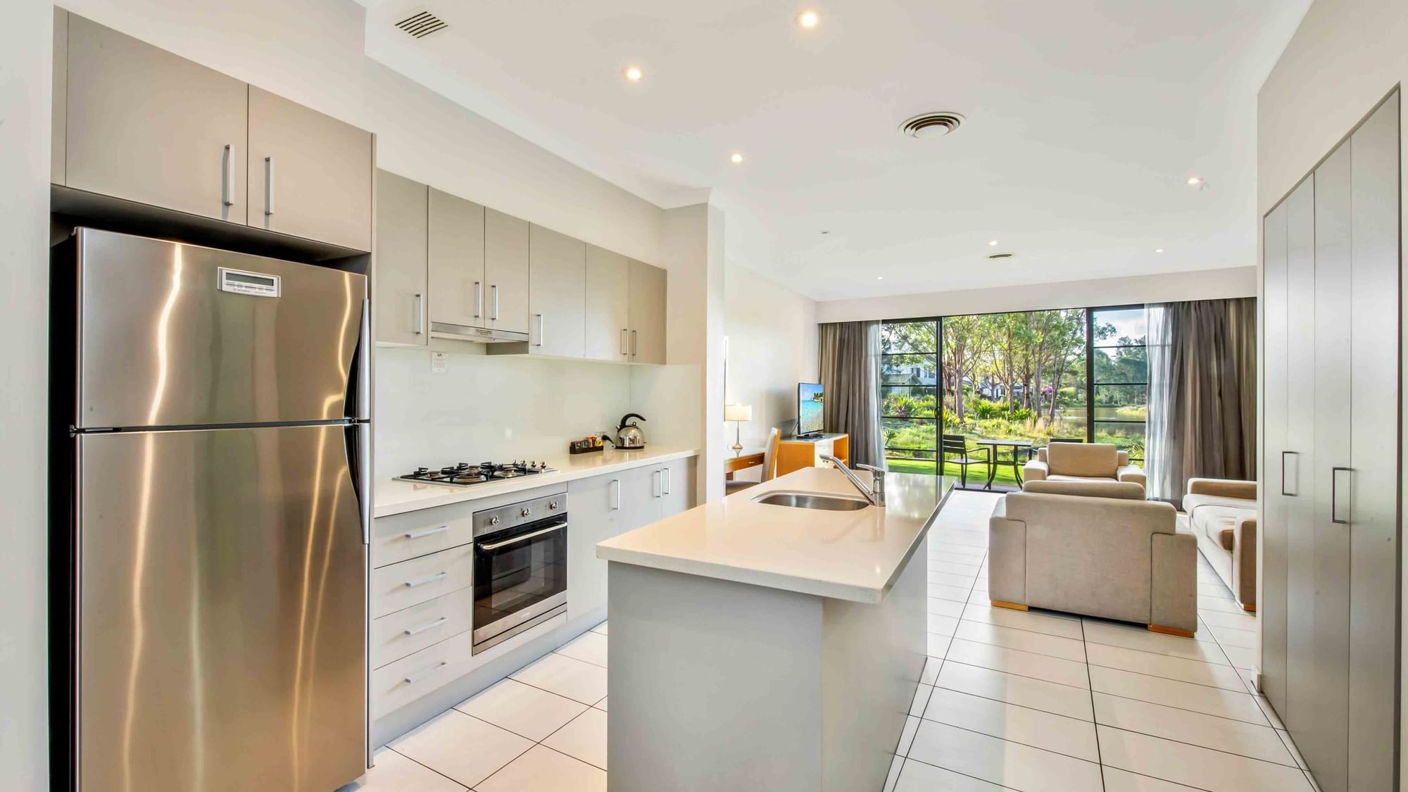 Two Bedroom Apartment kitchen with appliances opening to a bright living area at Mercure Kooindah Waters