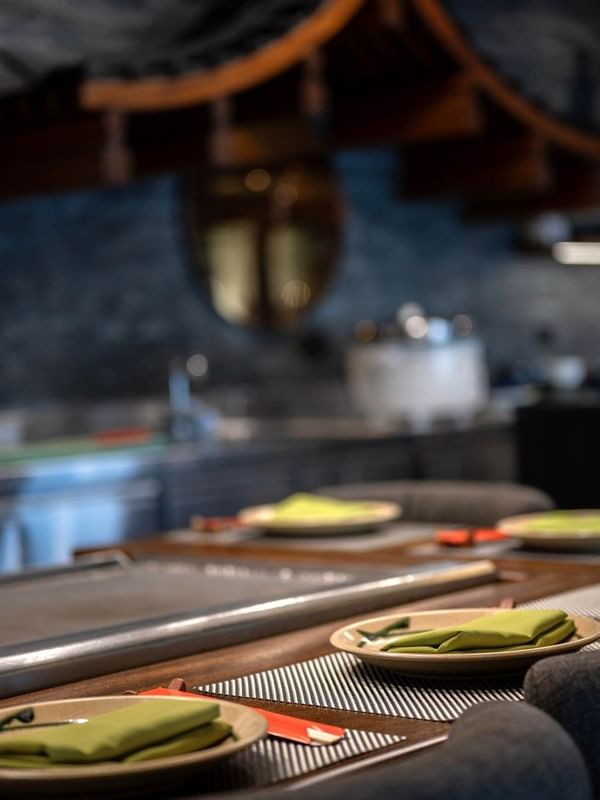 Plates with green napkins by a counter under a traditional wooden roof in Sazanami at Warwick Fiji Resort and Spa