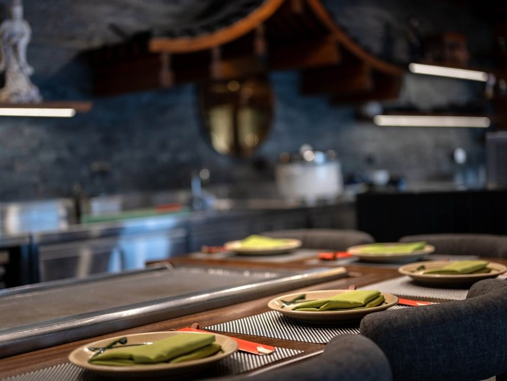 Plates with green napkins by a counter under a traditional wooden roof in Sazanami at Warwick Fiji Resort and Spa