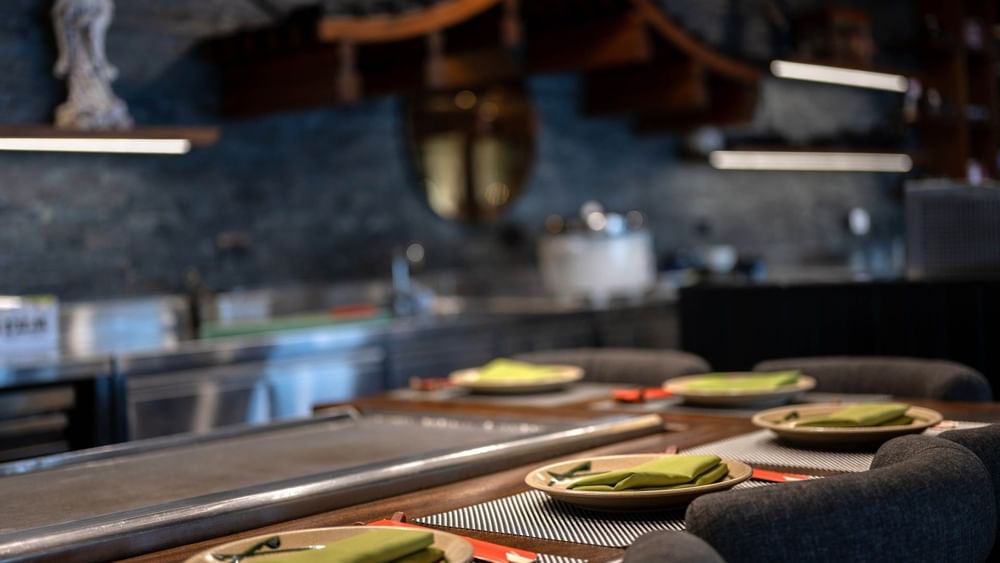 Plates with green napkins by a counter under a traditional wooden roof in Sazanami at Warwick Fiji Resort and Spa