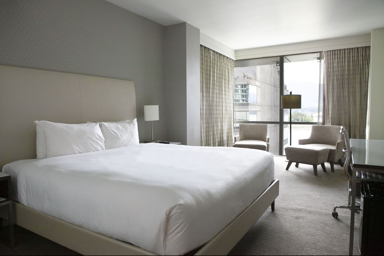 Bed, desk and lounge chairs in hotel room with window