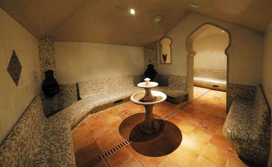 Massage room with mosaic seating, and a central stone fountain at Le Grand Hôtel des Thermes