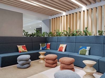 Modern lounge area with blue modular seating, colorful cushions, and wooden ceiling beams at UniLodge Auckland Central