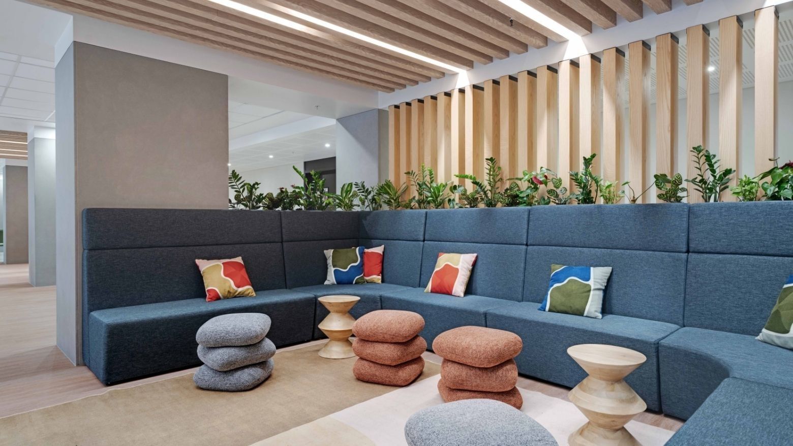 Modern lounge area with blue modular seating, colorful cushions, and wooden ceiling beams at UniLodge Auckland Central