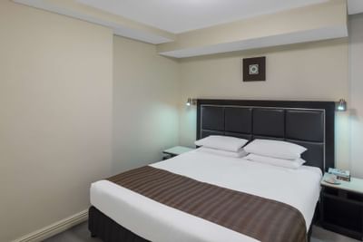 King bed with brown sheets at Nesuto Hotels