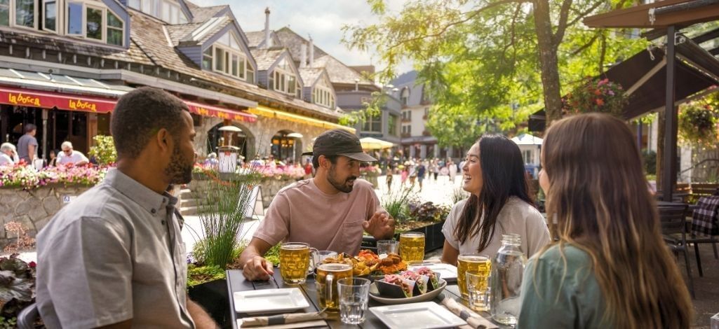 Friends enjoy food and drinks on an outdoor patio in Whistler Village.
